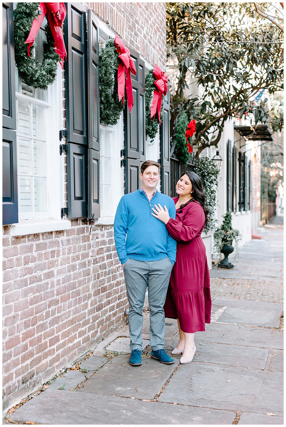 couple posed, smiling, christmas wreaths, engagement session