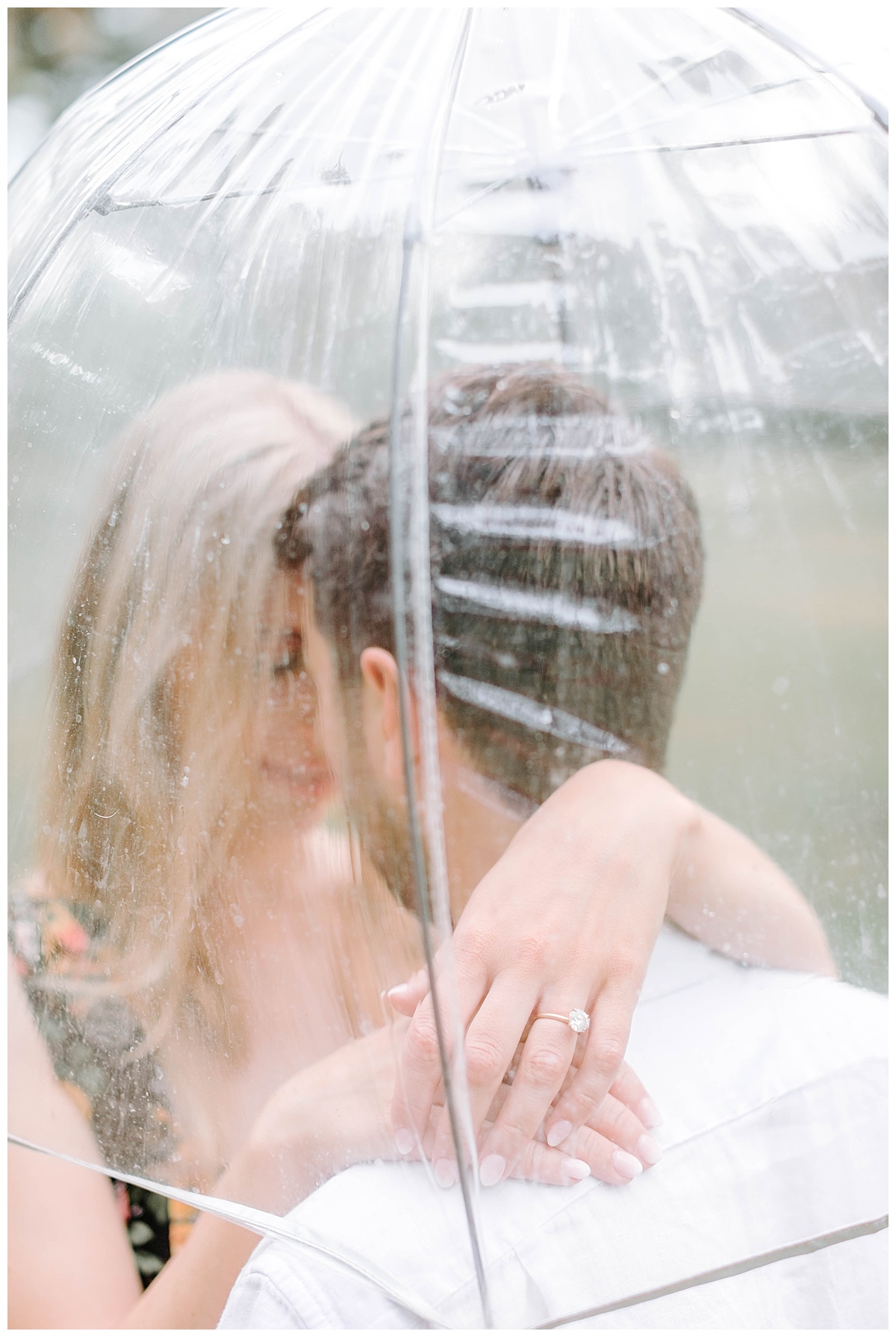 bride and groom under umbrella during rainy engagement session 